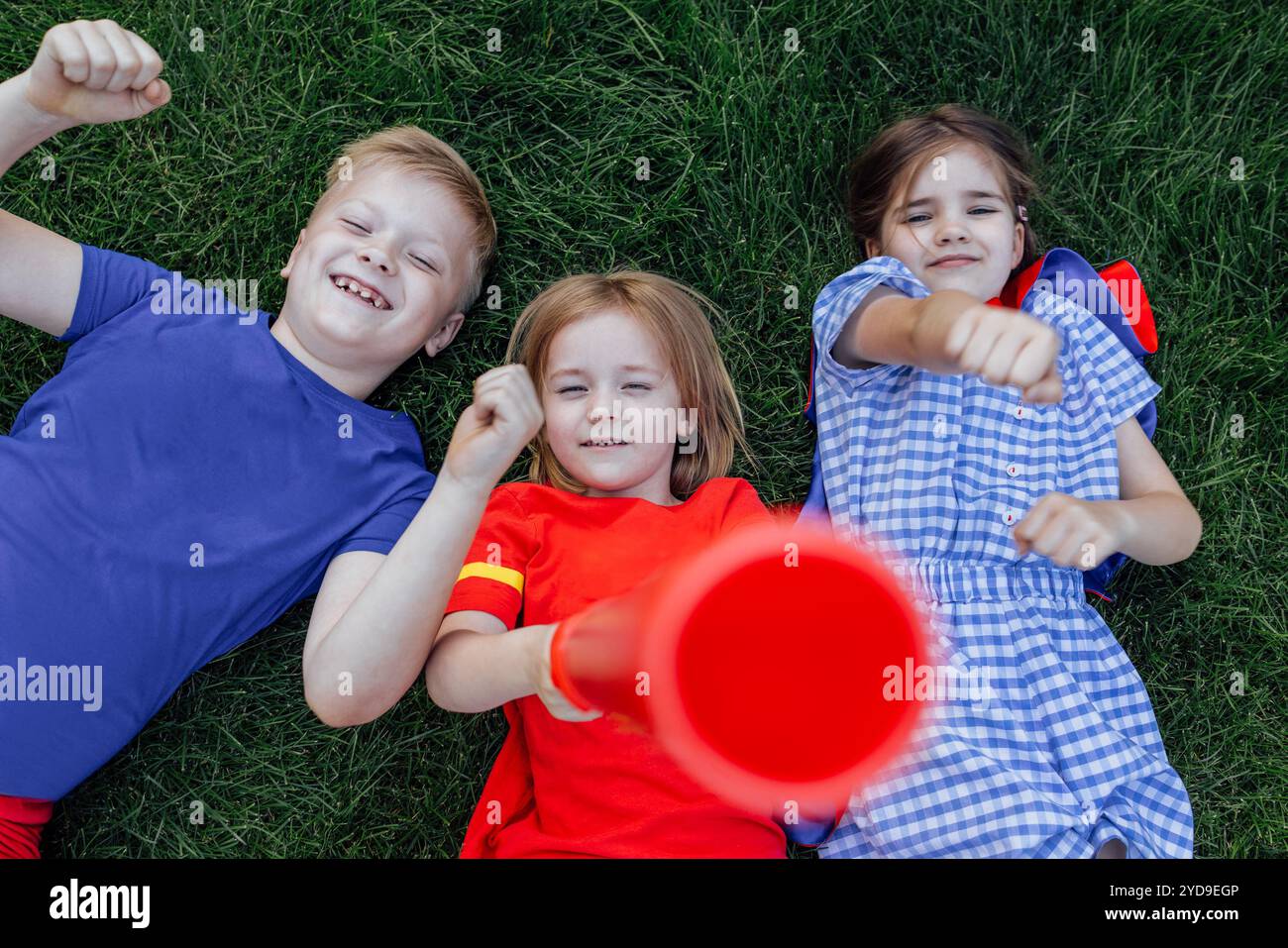 Kinder liegen und lachen auf dem grünen Rasen. Niedliche Kinder haben draußen auf der Wiese Spaß. Kleine Freunde haben eine tolle Zeit miteinander. Stockfoto
