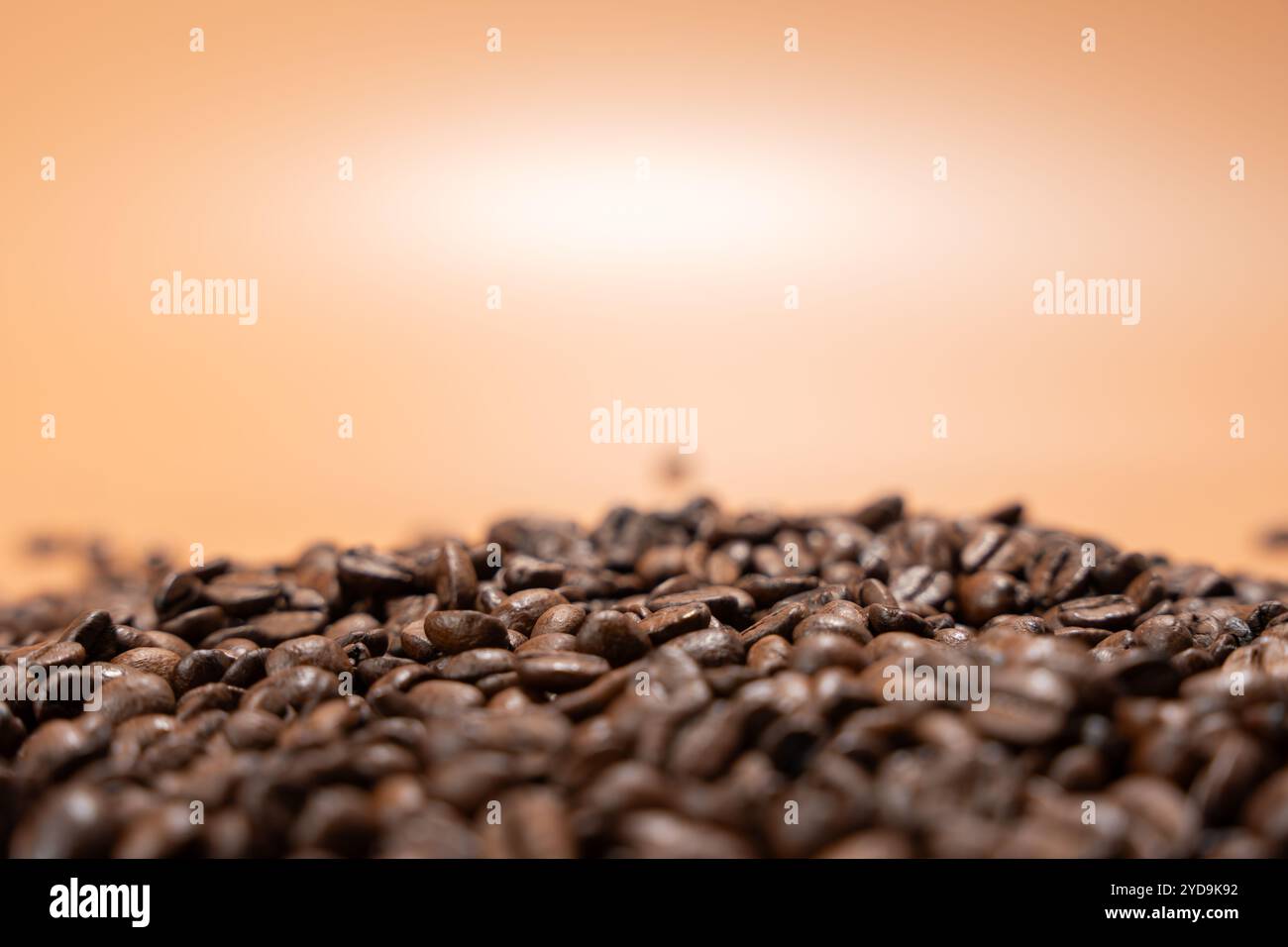 Ein Haufen Kaffeebohnen auf einem Tisch auf braunem Hintergrund. Die Bohnen werden verstreut und gestapelt, wodurch ein Gefühl von Tiefe und Textur entsteht. Das Bild erinnert an einen Stockfoto