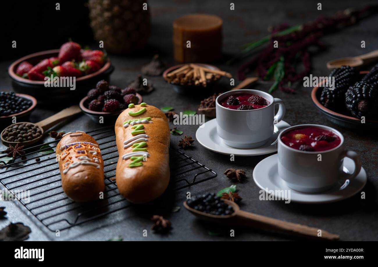 Guaguas de Pan mit Tassen Colada Morada, traditionelles ecuadorianisches Essen für den Tag der Toten, umgeben von den Zutaten, um die Colada wieder zu kochen Stockfoto