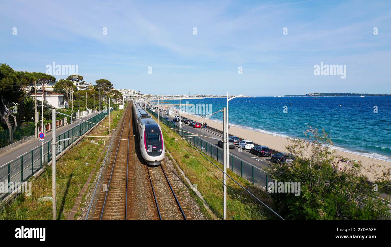 Ein TGV-Hochgeschwindigkeitszug, der entlang der malerischen Mittelmeerküste in Frankreich gleitet. Die Bahnstrecke verläuft parallel zum glitzernden blauen Meer. Stockfoto