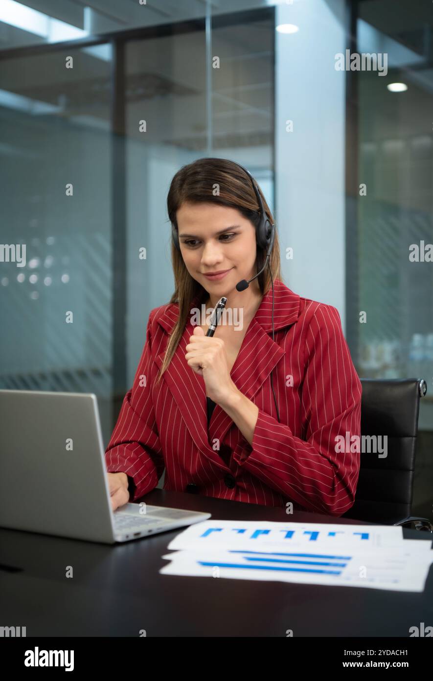 Junge Frau, die in einem Callcenter arbeitet, das als Berater für verschiedene Informationen über Kunden fungiert, die anrufen, um sich zu erkundigen oder um eine zu bitten Stockfoto