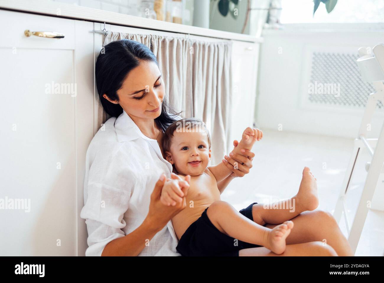 Eine junge attraktive Frau hält ihren lächelnden Sohn in den Armen. Stockfoto