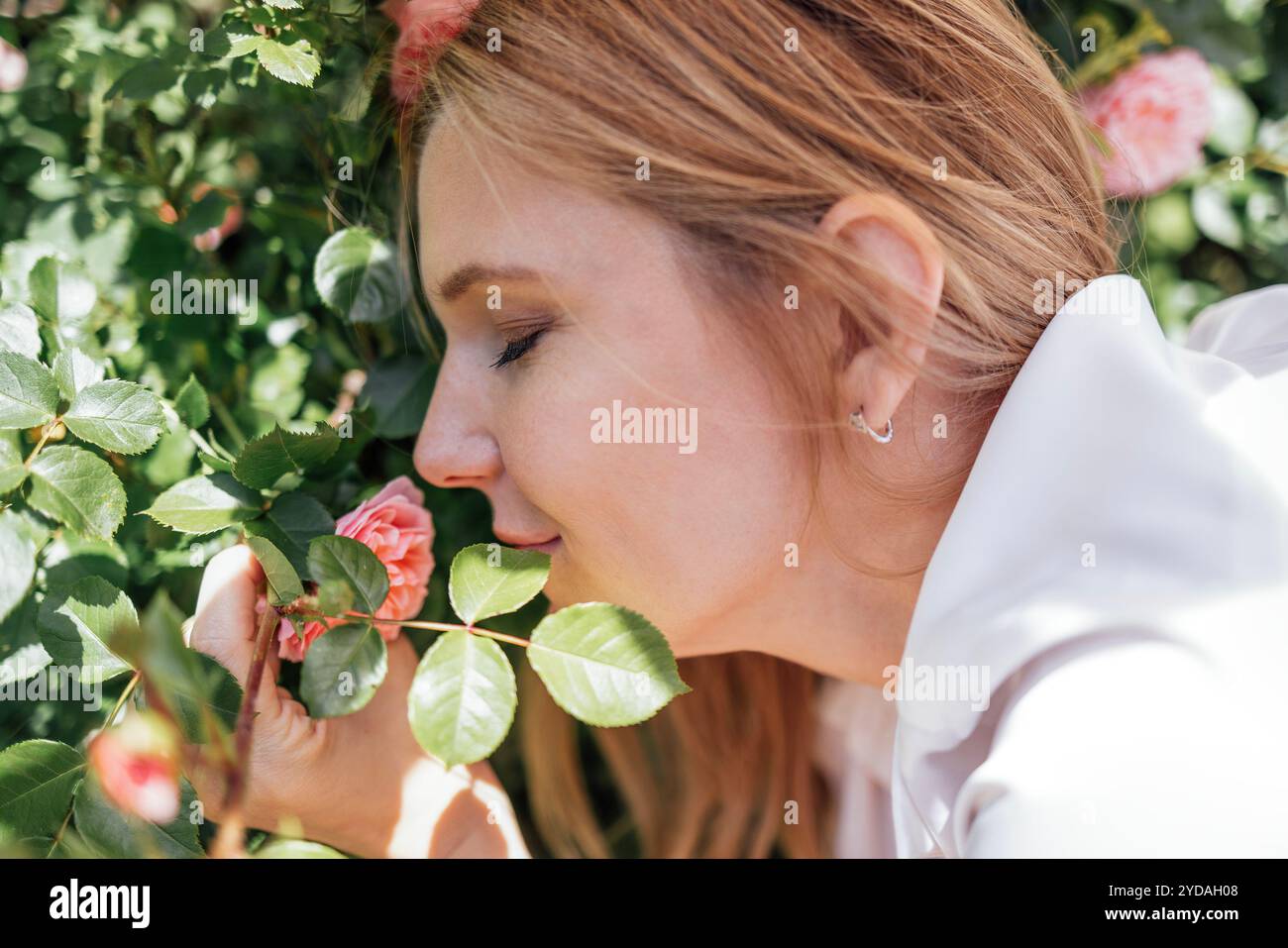 Nahaufnahme eines weiblichen Porträts einer jungen attraktiven Frau mit roten Blumen Stockfoto