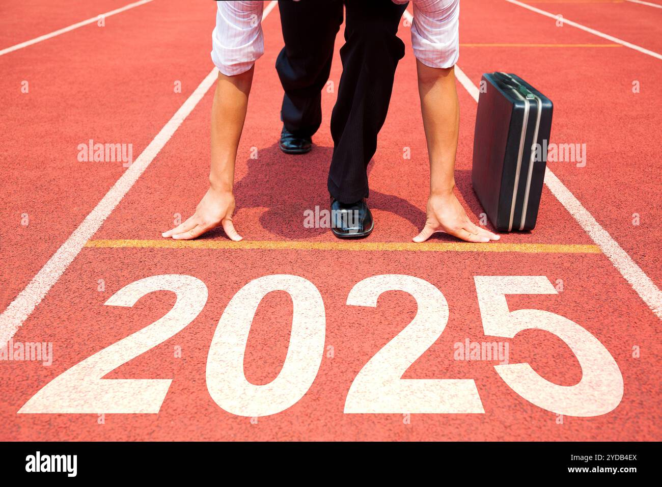 Happy New Year 2025 Konzept. Geschäftsmann, der sich auf die Leichtathletikbahn vorbereitet, die mit dem Jahr 2025 graviert ist. Vorbereitung auf das neue Jahr Stockfoto