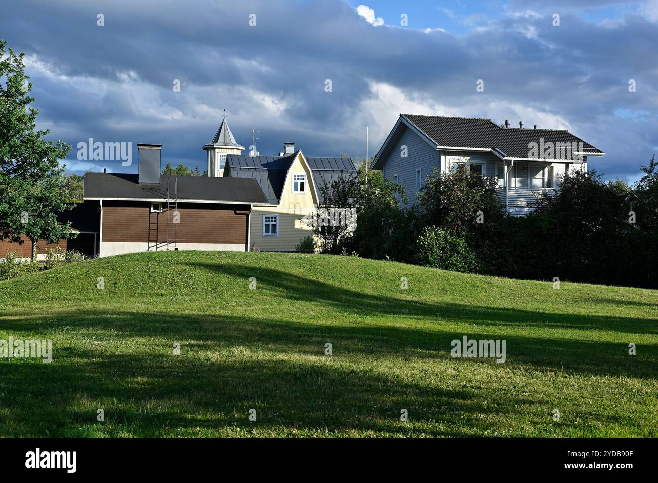 Eine ruhige Wohngegend mit hölzernen, gelben und grauen Häusern, die von Sonnenlicht und Schatten hervorgehoben werden Stockfoto