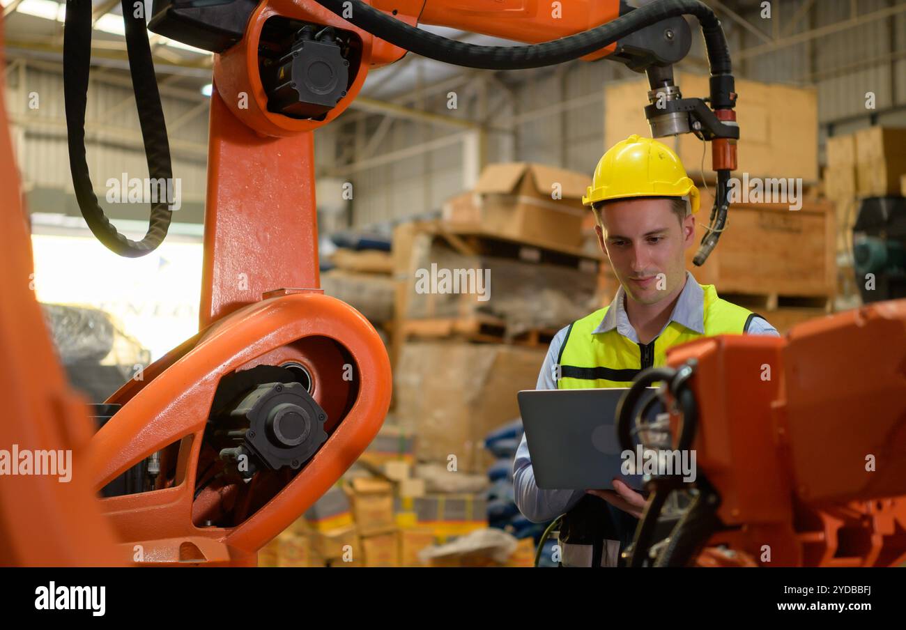 Ein männlicher Ingenieur, der die Funktion eines Schweißroboters überprüft. Für die präzise Schweißkontrolle schnell und hochsicher Stockfoto