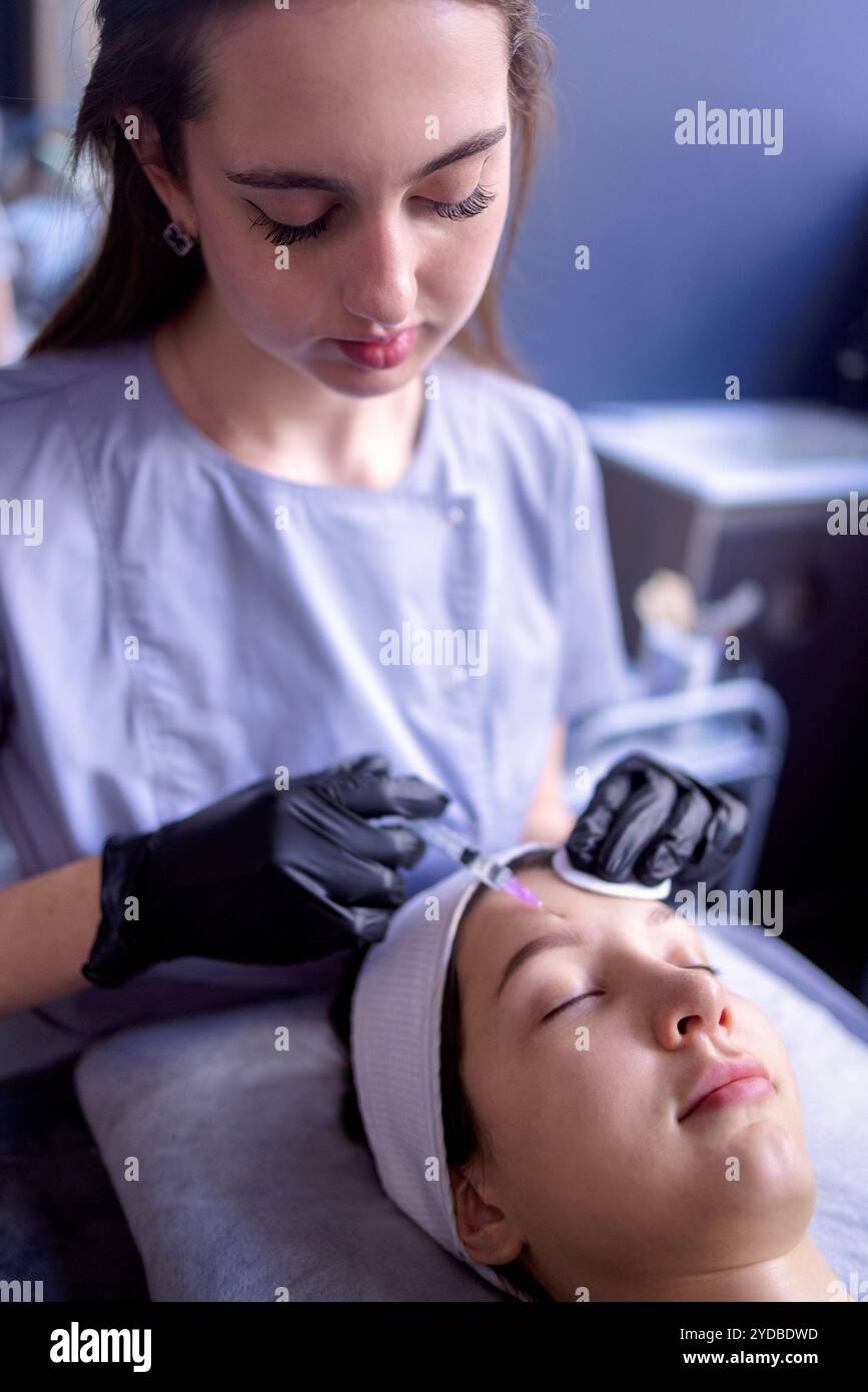 Beauty-Injektionen. Eine Kosmetikerin in schwarzen Handschuhen spritzt sich Stockfoto