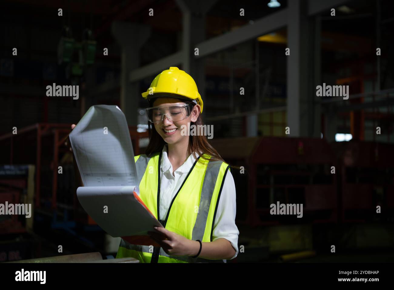 Die weibliche Führungskraft arbeitet im Auditbereich. Sie arbeitet daran, die Qualität der Arbeit in schweren Industrieanlagen nachts zu überprüfen Stockfoto