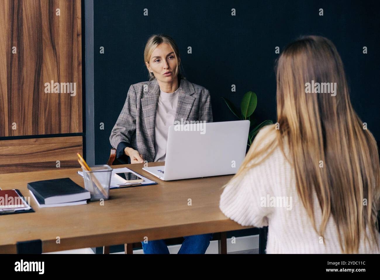 Eine Frau, die an einem Schreibtisch in einem Büro sitzt, befragt einen Kandidaten für eine Position. Stockfoto