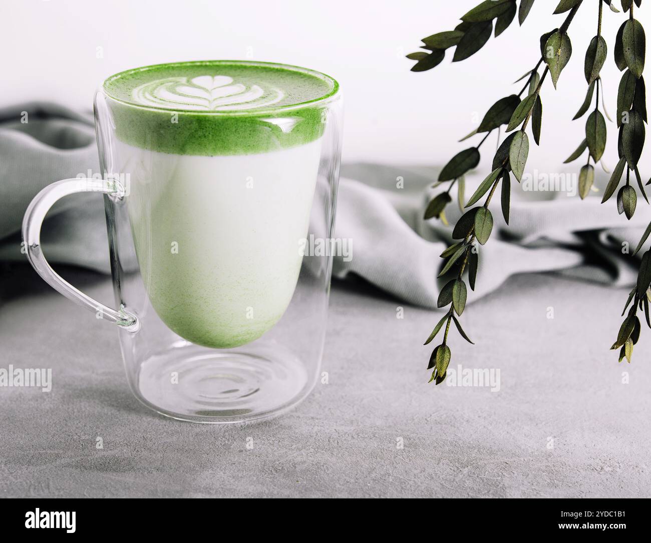 Ein Glas heißer Matcha-Grüntee-Latte mit Tulpenmuster Stockfoto