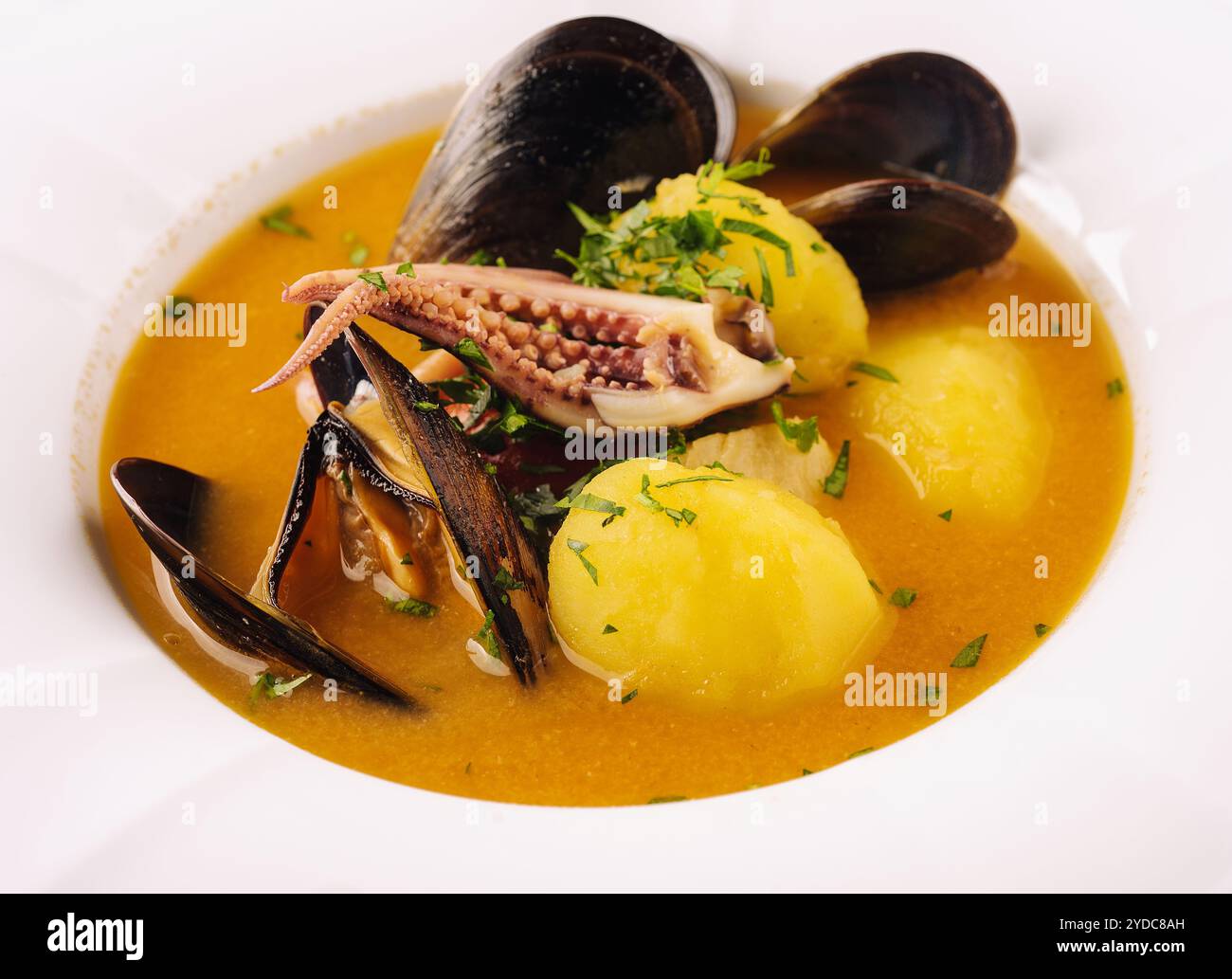 Cremige Meeresfrüchte-Suppe mit Muscheln, Kartoffeln und kleinen Tintenfischen Stockfoto