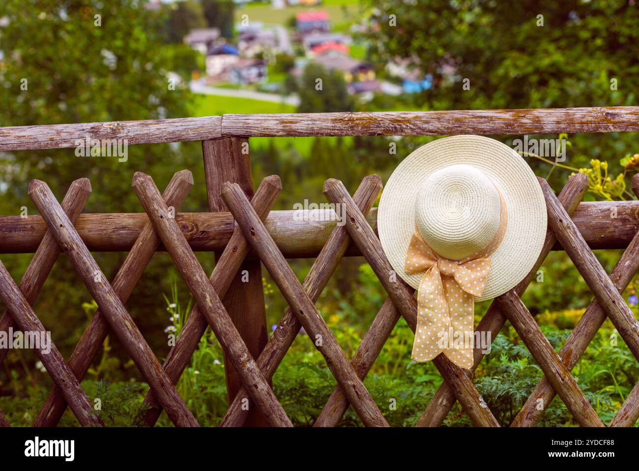 Weibliche Sommerhut hängt am hölzernen rustikalen Zaun Stockfoto