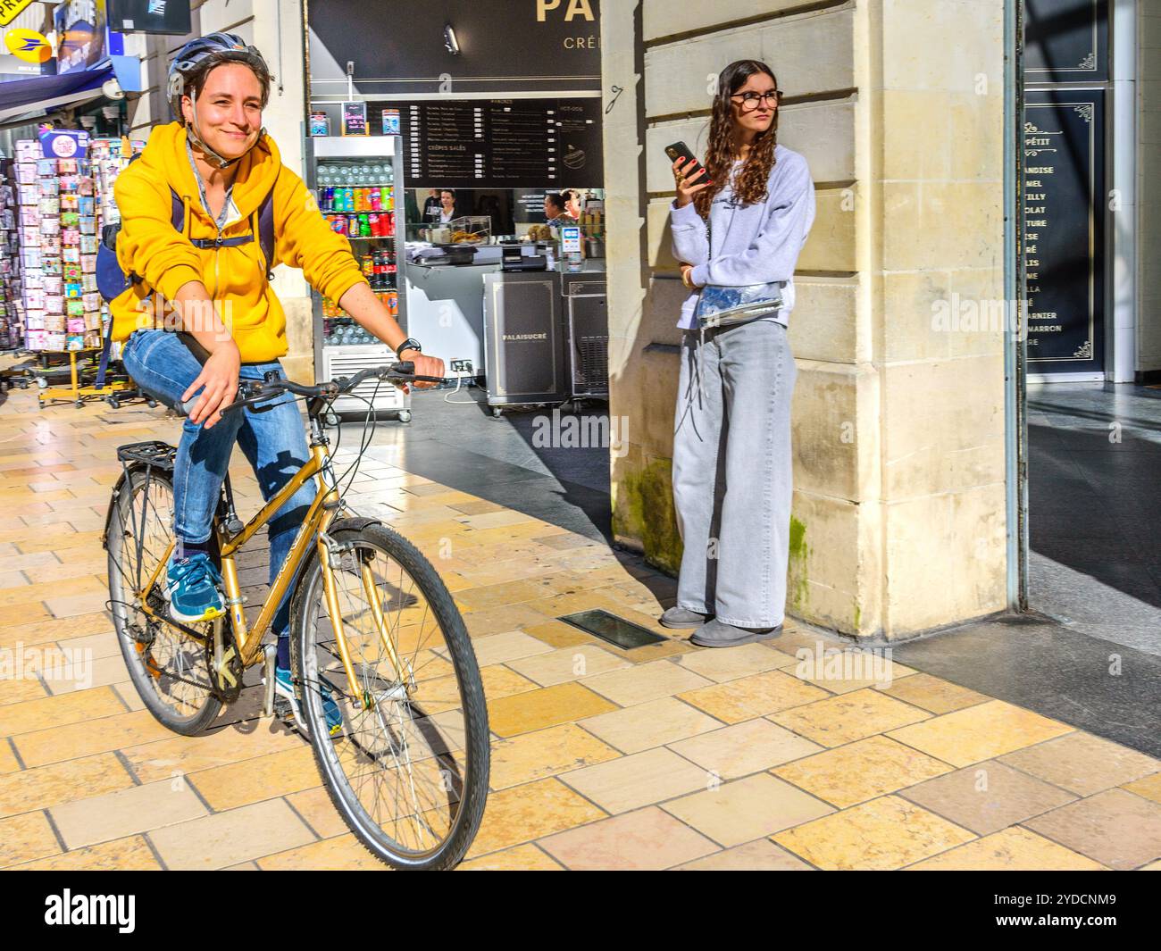 Frau, die mit dem Fahrrad neben der Straßenbahn auf der nicht mit dem Fahrzeug befahrenen Straße im Stadtzentrum unterwegs ist - Tours, Indre-et-Loire (37), Frankreich. Stockfoto