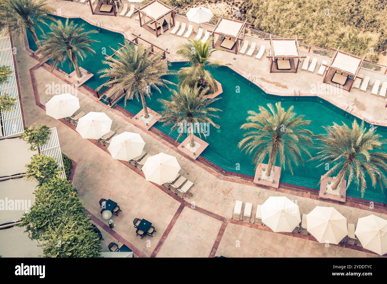 Hotel am Pool mit Sonnenschirmen und Palmen Stockfoto