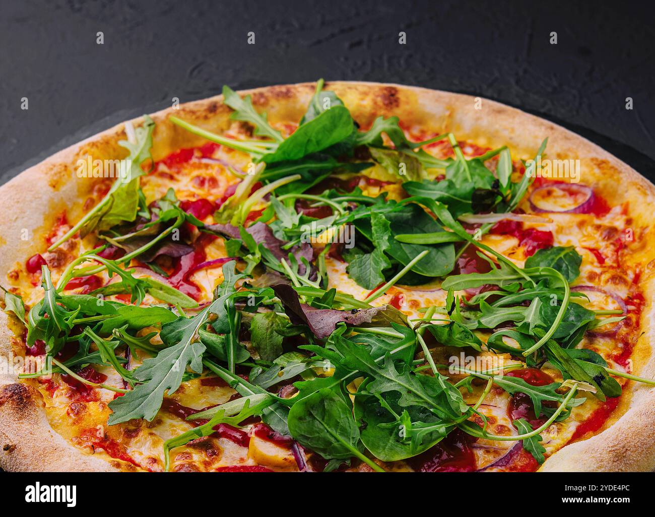 Pizza mit Rucola auf schwarzem Brett Stockfoto