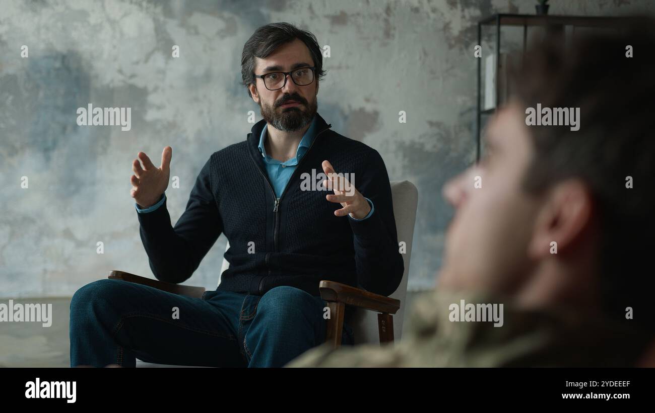 Erfahrener Kaukasier reifer Mann Spezialist für Psychologe Therapeut erklärt Gesten über Rehabilitation mit Militärsoldaten Stockfoto
