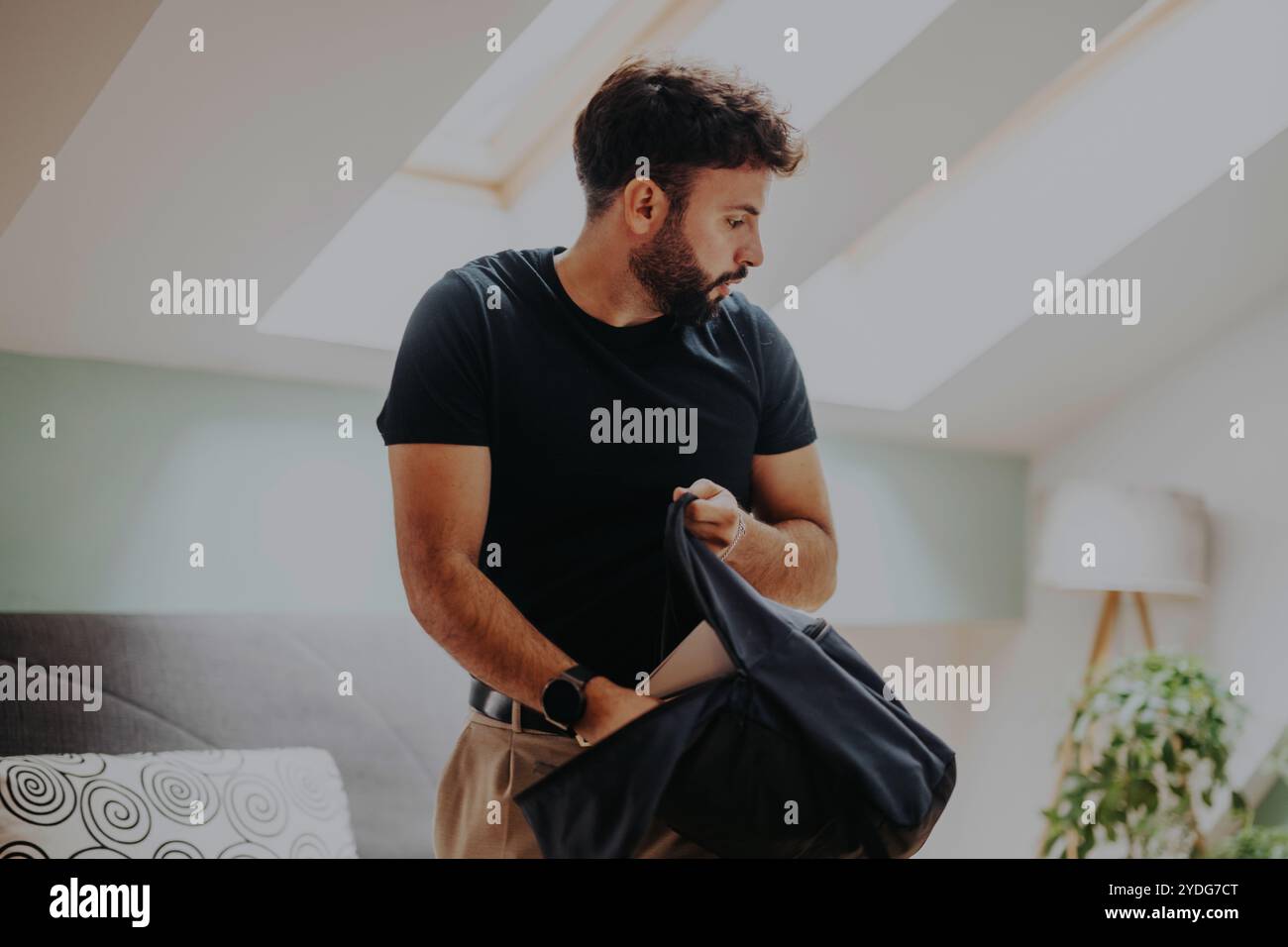 Junger Student, der seine Tasche in einem hellen, modernen Zimmer organisiert Stockfoto