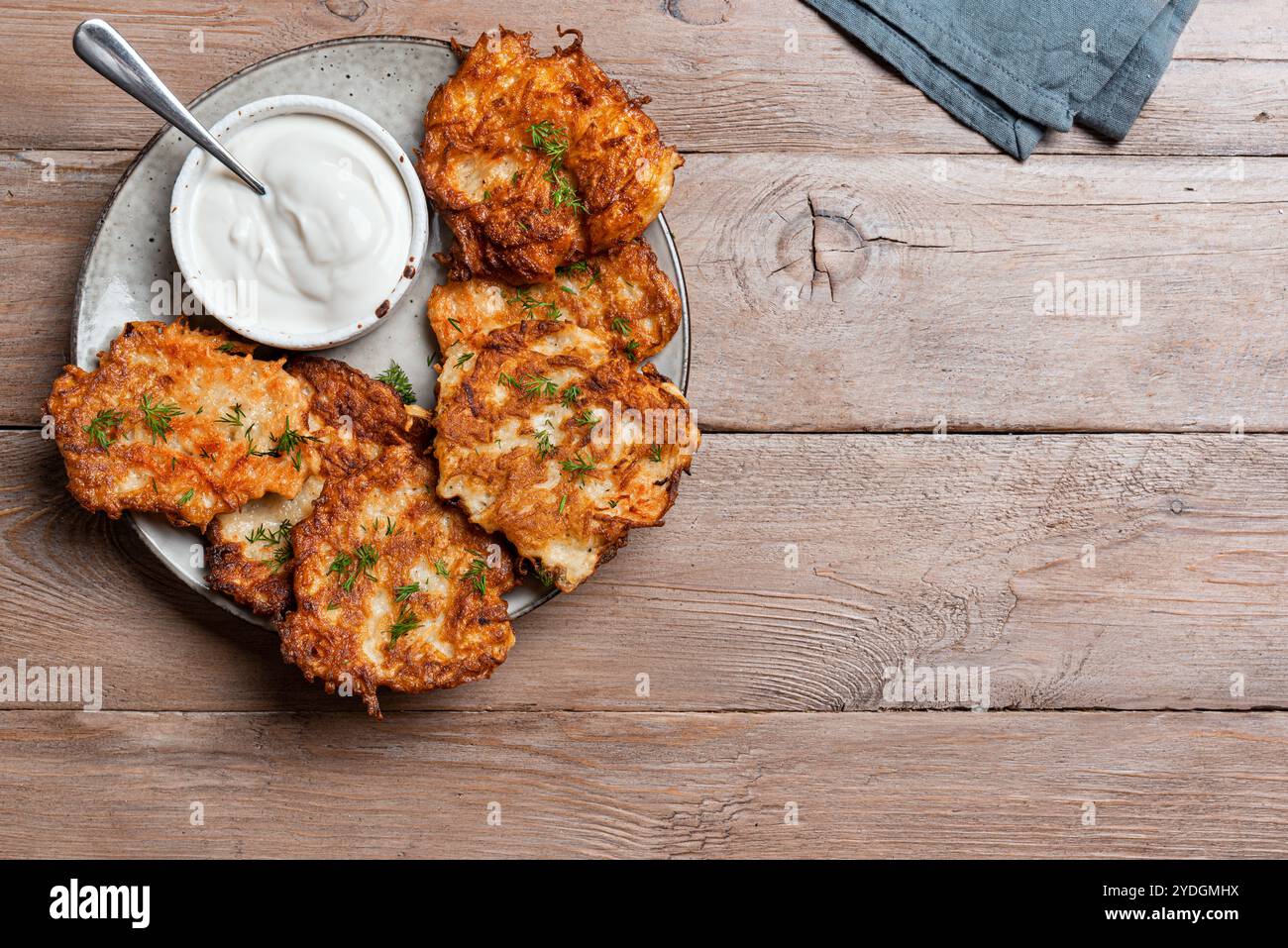 Kartoffellatkes mit Sauerrahm auf hölzernem Hintergrund, Draufsicht, Kopierraum. Traditionelle jüdische Latkes oder Levivot. Kartoffelrösti. Stockfoto