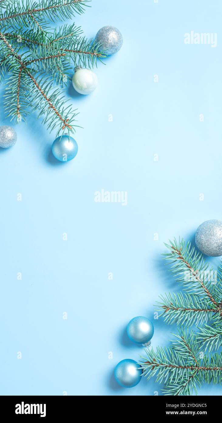 Blaue und silberne Weihnachtskomposition mit Tannenzweigen, Kugeln auf hellblauem Hintergrund, mobile Tapete, Kopierraum. Weihnachten festlich kreativ DE Stockfoto