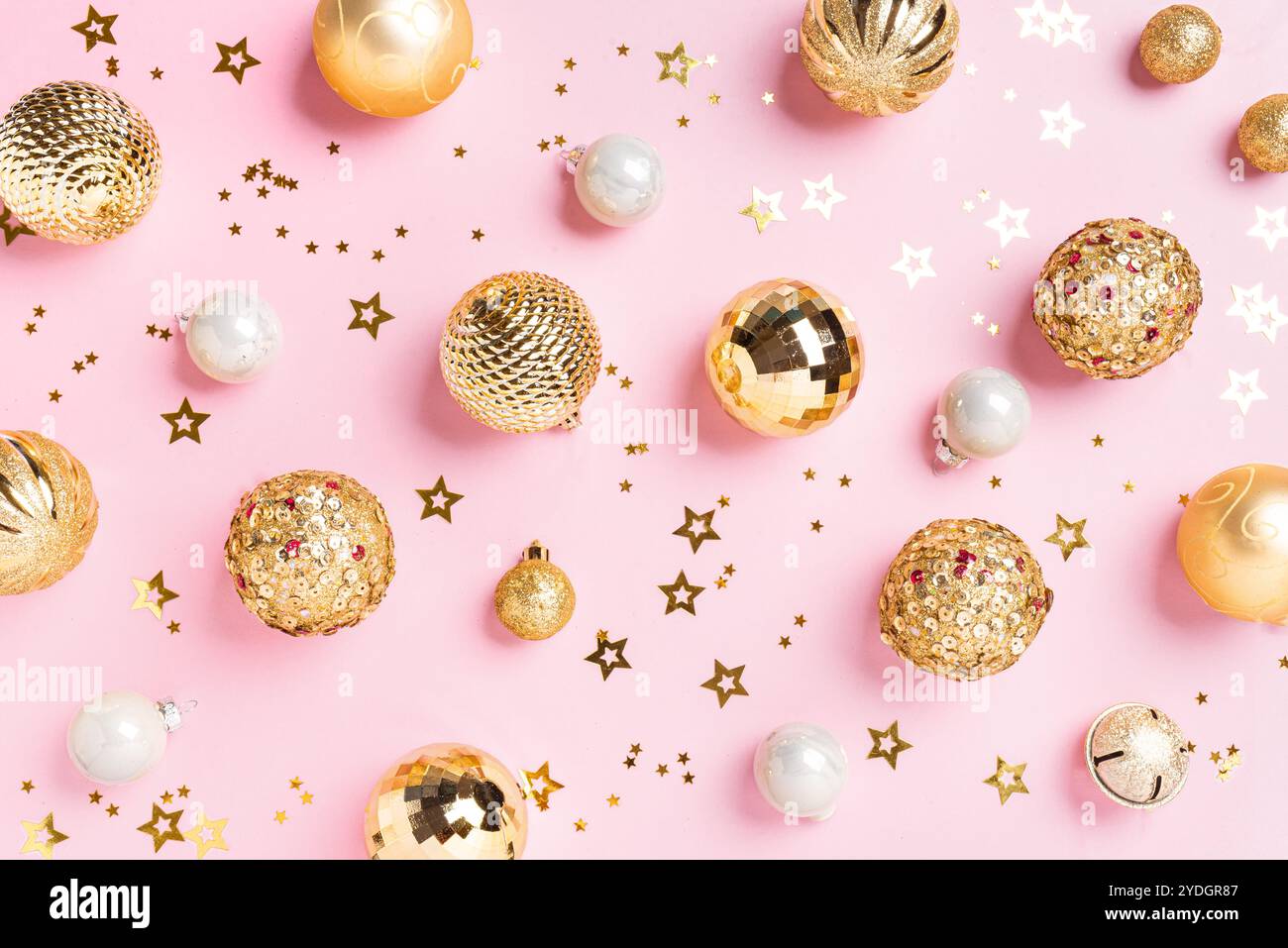 Weihnachtsglanz goldene Kugeln auf rosa Pastellhintergrund, festliche Komposition. Weihnachtliches Design mit goldenen Ornamenten und Konfetti. Stockfoto