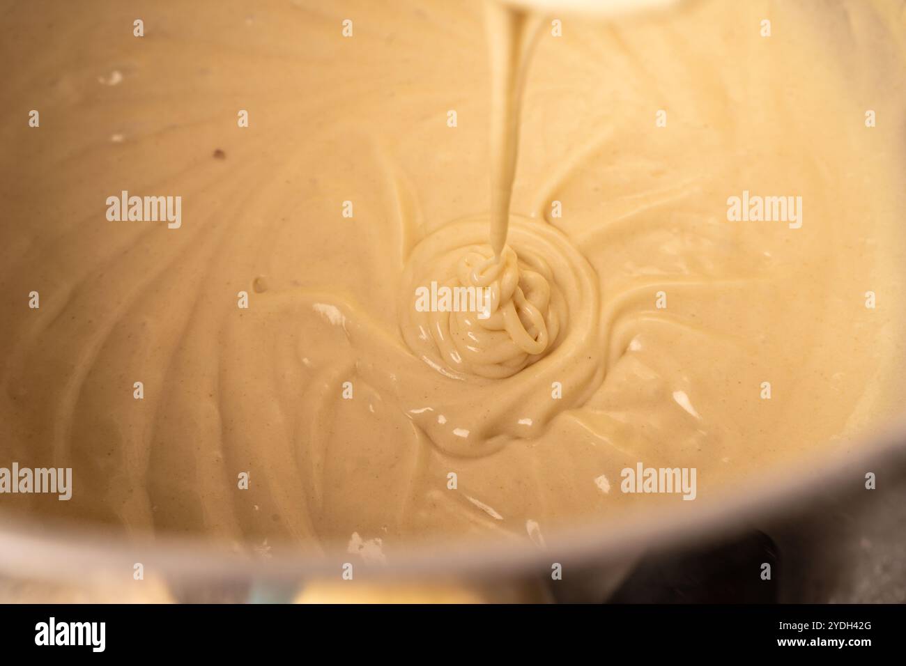 Der Teig wird in einem Planetenmischer verknetet. Der Pfannkuchen- oder Pie-Teig tropft vom Mixer. Hochwertige Fotos Stockfoto
