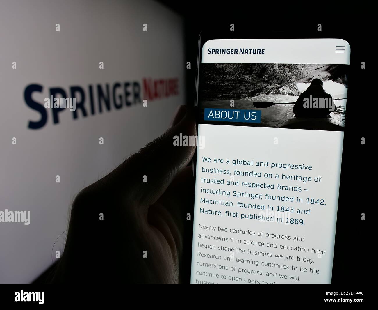 Person mit Smartphone und Webseite des akademischen Verlags Springer Nature auf dem Bildschirm mit Logo. Konzentrieren Sie sich auf die Mitte des Telefondisplays. Stockfoto