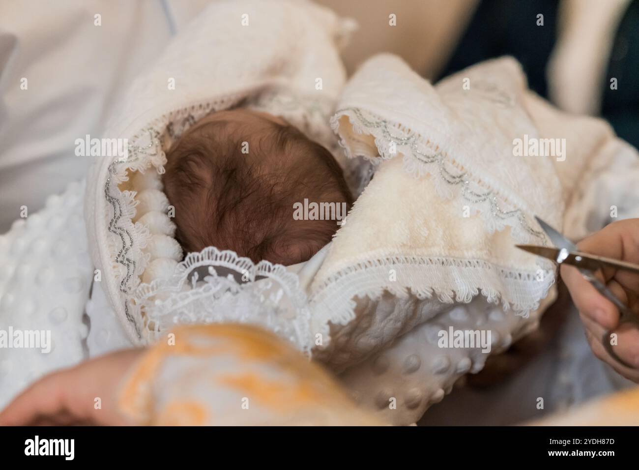 Der zärtliche Moment eines Neugeborenen, der auf eine Segenszeremonie vorbereitet wird. Stockfoto