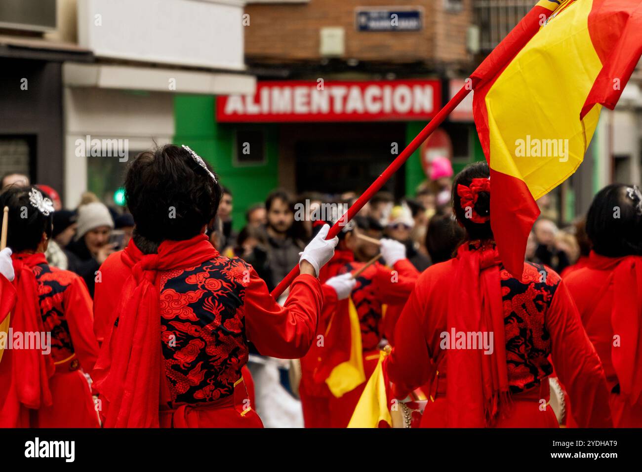 Chinesische Frauen spielen Trommeln und halten die spanische Flagge auf der Neujahrsparade Stockfoto