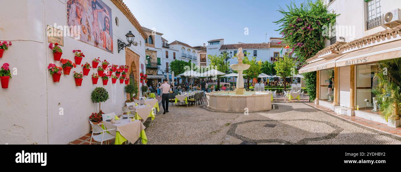 Der Brunnen sprüht Wasser auf der Plaza de los Naranjos, einem beliebten Platz in Marbella, Spanien, während Touristen und Einheimische Erfrischungen in einem Ou genießen Stockfoto