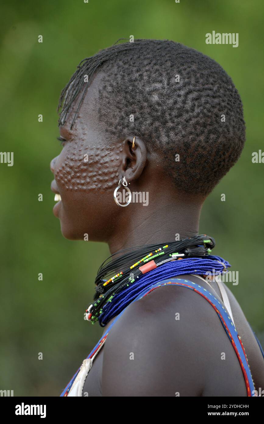 Ein lächelndes Karimojong-Mädchen mit Gesichtstätowierungen in Kotido, Karamoja Uganda. Unter den Karimojong-Stämmen symbolisieren die Gesichtstattoos Schönheit. Stockfoto