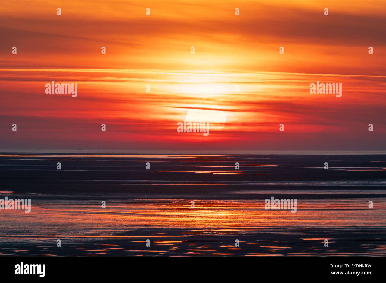 Roter Sonnenuntergang über einem leeren Strand in Baie de Somme, Frankreich, Sonne versteckt sich hinter den Wolken Stockfoto