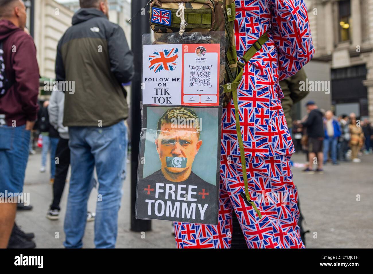 London, Großbritannien. OKTOBER 2024. Man in union Jack Suit trägt ein Poster „Free tommy“ auf dem Rücken, als Tausende sich für die von Tommy Robinson organisierte Kundgebung „Unite the Kingdom“ versammelten, der wegen seiner Haft nicht anwesend war, und in Victoria den marsch friedlich zum Parlamentsplatz machten, wo ein neuer Dokumentarfilm „Lawfare“ gezeigt wurde. Stand Up to Rassismus mobilisierte einen Gegenprotest auch mit Tausenden von Menschen, die sich friedlich am anderen Ende von whitehall versammelten. Credit Milo Chandler/Alamy Live News Stockfoto