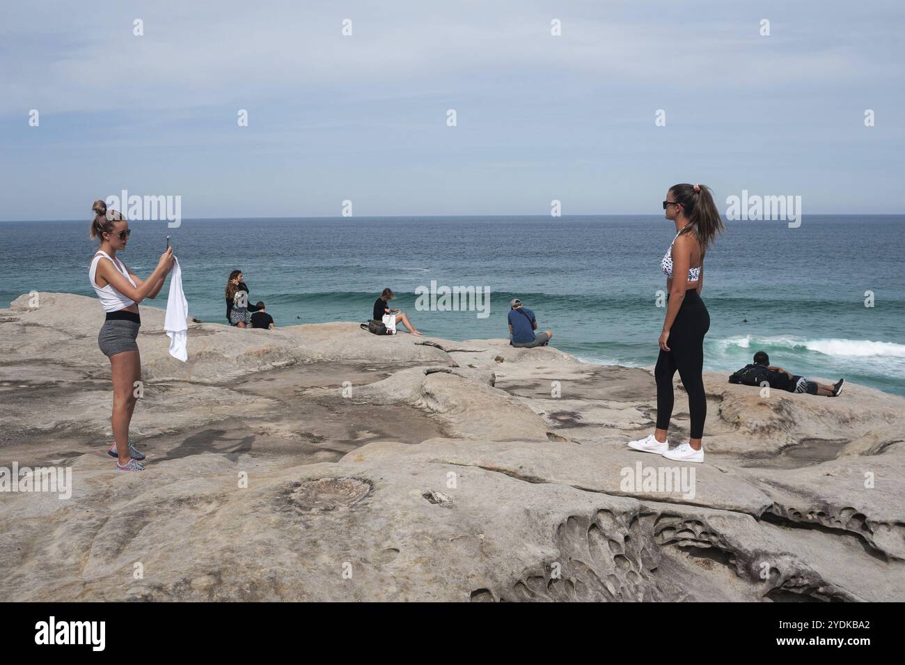 27.09.2019, Sydney, New South Wales, Australien, Eine junge Frau fotografiert ihre Freundin auf den Klippen am Tamarama Point. Touristen schauen nach, um zu sehen Stockfoto