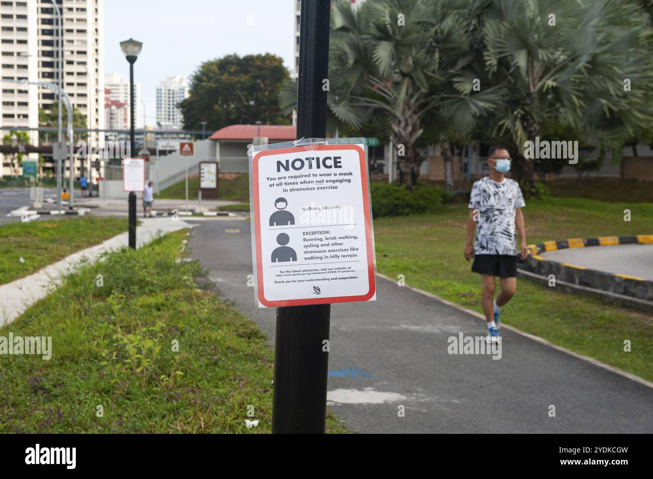 29.04.2020, Singapur, Republik Singapur, Asien, Ein Mann mit Gesichtsmaske geht an einem COVID-19-Schild vorbei, das obligatorische Maßnahmen zur weiteren Limi anzeigt Stockfoto