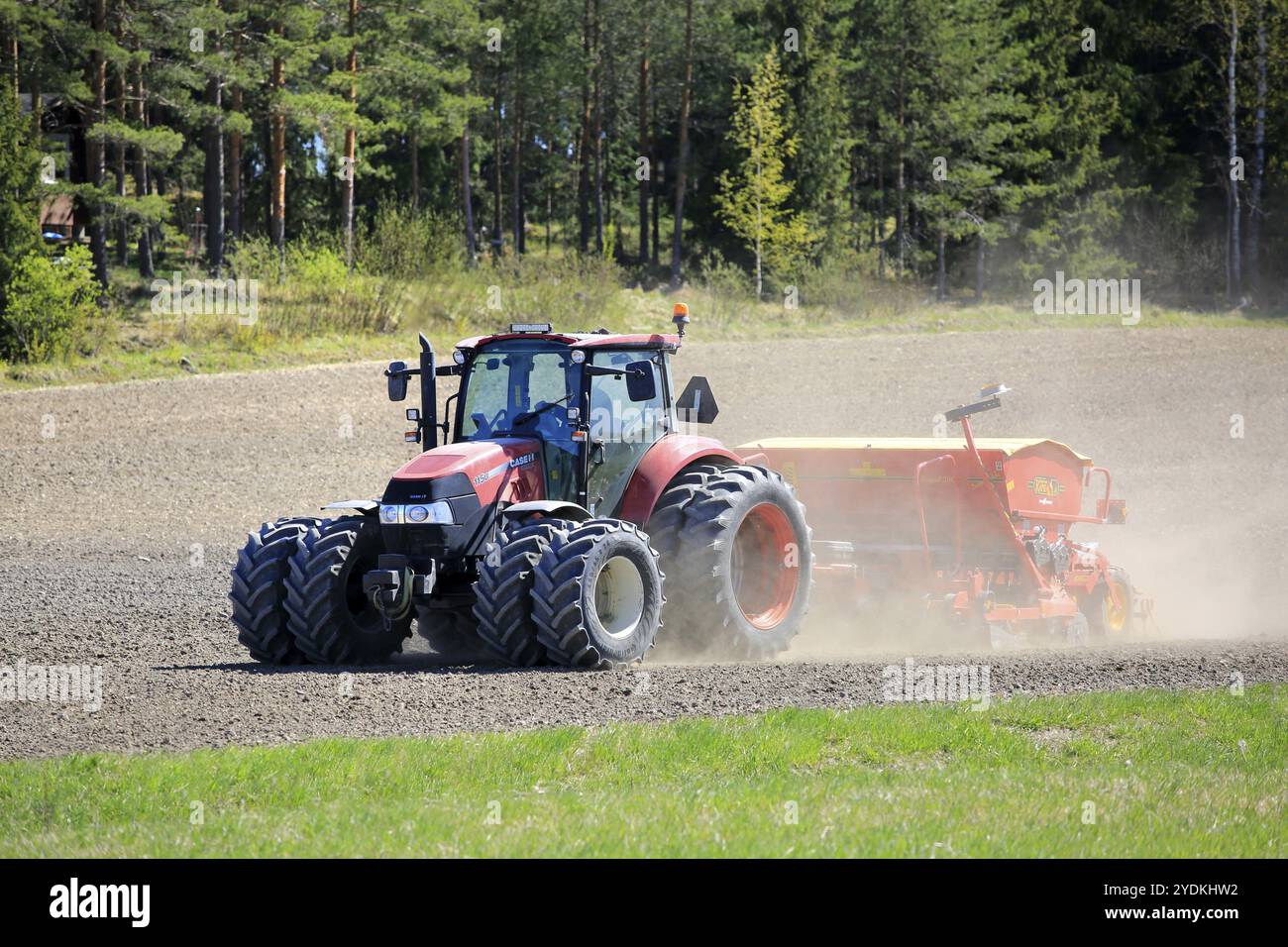 Arbeiten im Feld mit dem roten Case IH 115U Farmall-Traktor und der Saatmaschine Vaderstad Rapid Super 300C an einem Frühlingstag. Salo, Finnland. Mai 2024 Stockfoto