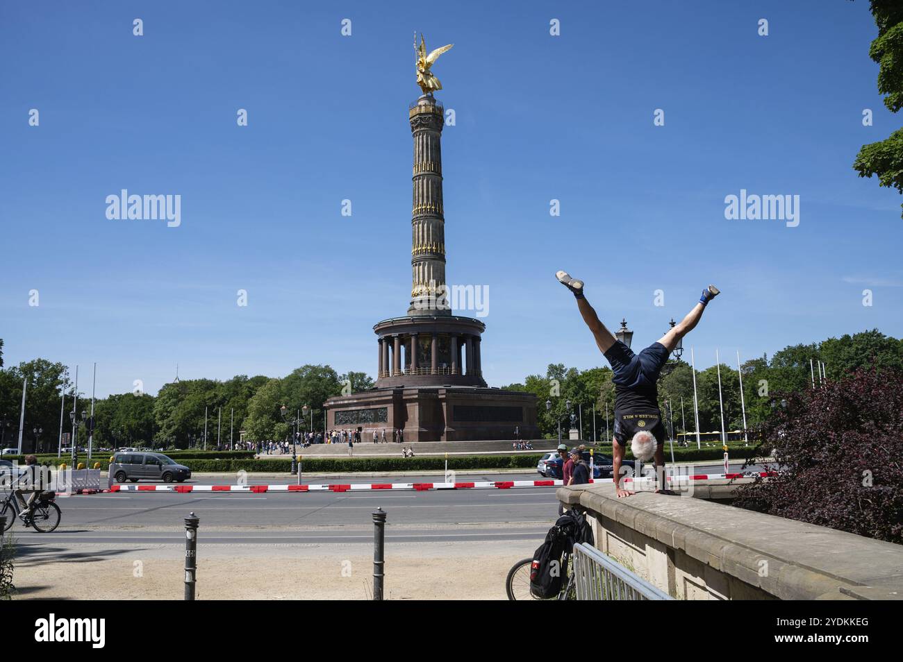 09.05.2024, Berlin, Deutschland, Europa, Ein Mann steht auf einer niedrigen Mauer vor der Siegessäule am Großen Stern im Tiergarten auf einer sonnigen Sonne Stockfoto
