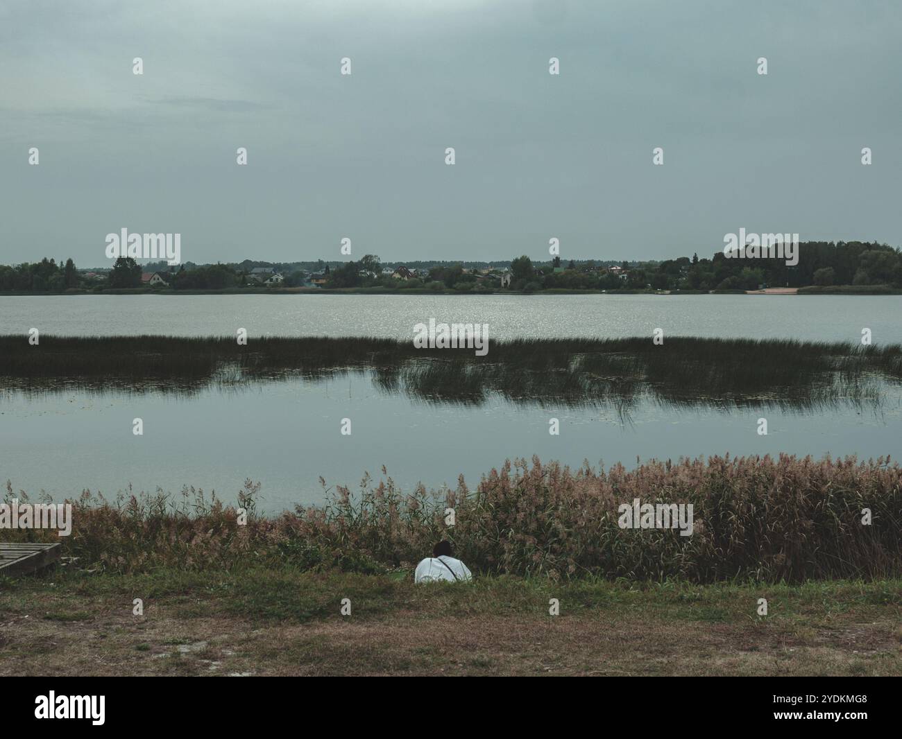 Einsame Frau, die allein am Herbstfluss sitzt, zurück view.autumn Landschaft.Riga.Lettland.30.09.2024 Stockfoto