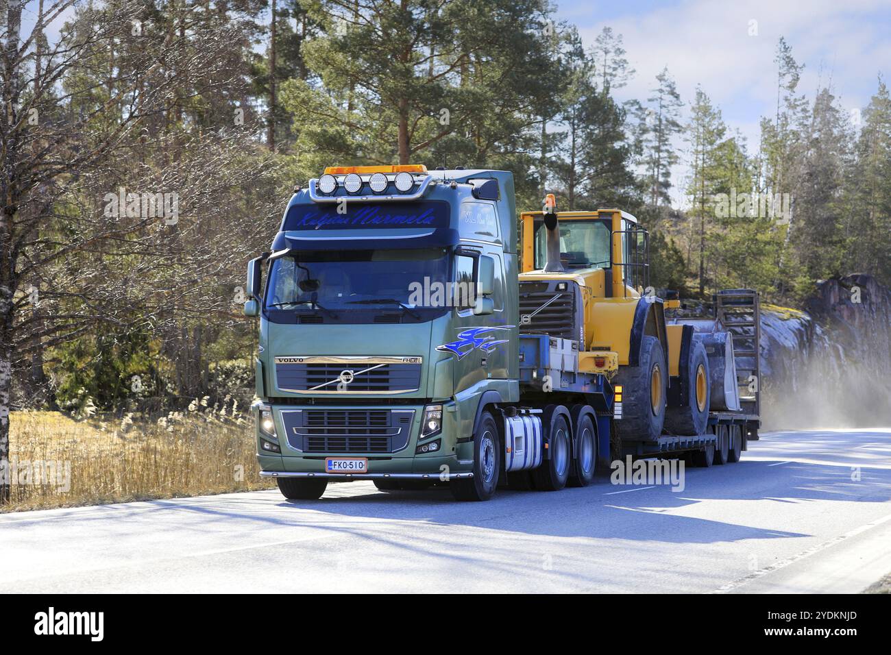 Der grüne Volvo FH16-Lkw transportiert den Volvo L150F Radlader auf einem Tieflader-Auflieger entlang der Autobahn. Salo, Finnland. April 2024 Stockfoto