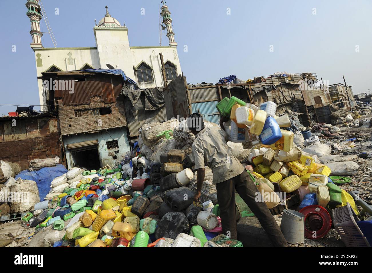 11.12.2011, Mumbai, Maharashtra, Indien, Asien, ein Mann sortiert Plastikbehälter zum Recycling in Mumbais Dharavi-Slum mit den Moinia Masjid, Dharavi's Stockfoto