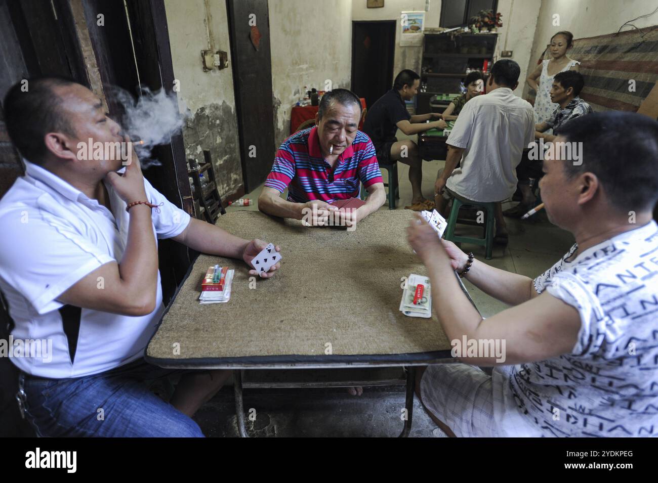 04.08.2012, Chongqing, China, Asien, Chinesen rauchen Zigaretten, während sie an einem Tisch sitzen und Karten spielen im 18 Treppenbereich im alten Schlepptau Stockfoto