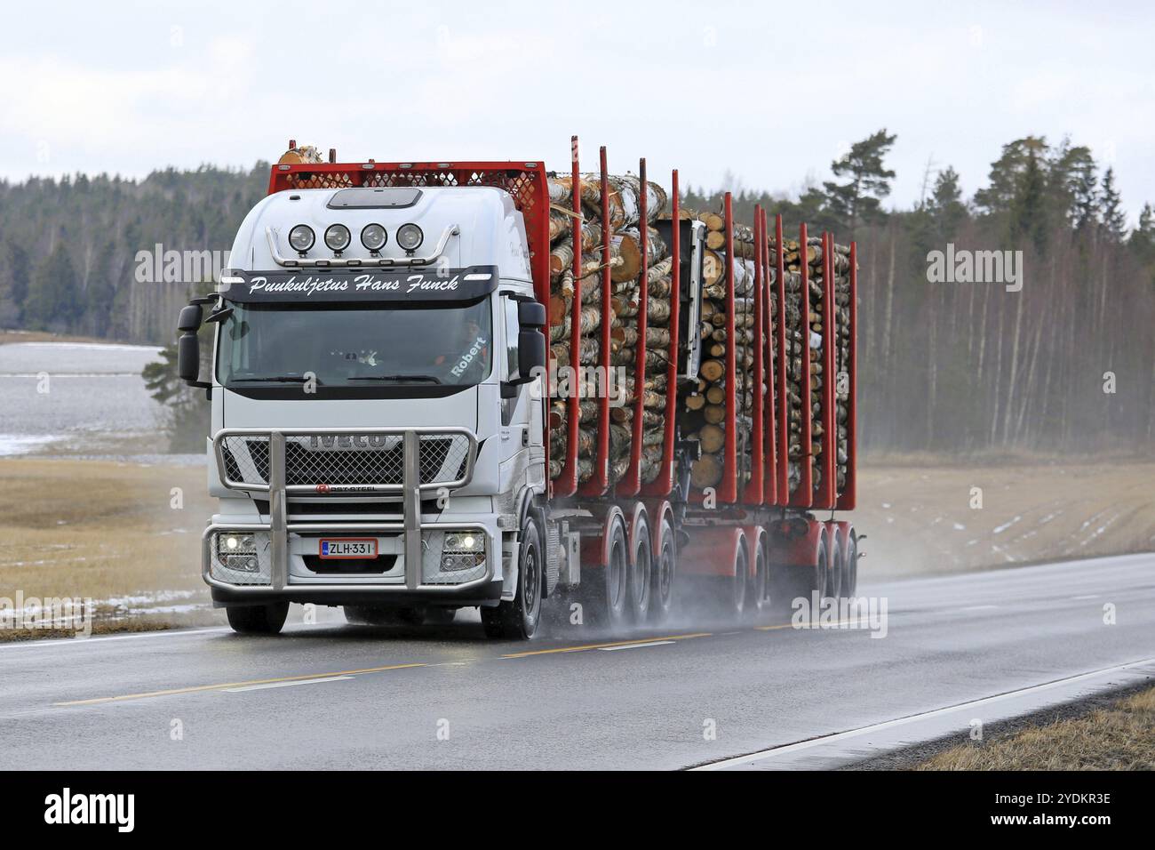 SALO, FINNLAND, 4. MÄRZ 2017: Der weiße Iveco Stralis 560 Holzfällerwagen von Puukuljetus Hans Funck transportiert im Winter eine Ladung Baumstämme auf nasser Straße in so Stockfoto