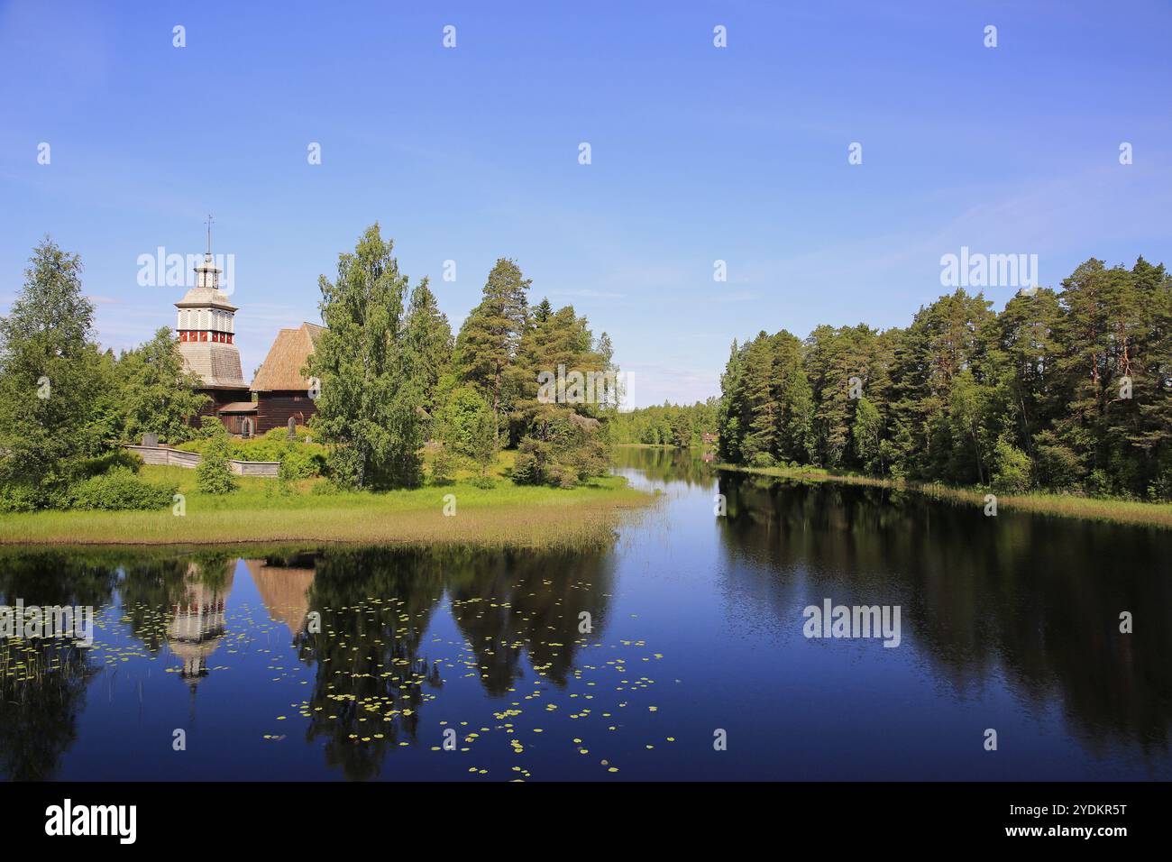 Finnischer blauer See und Himmelslandschaft mit UNESCO-Weltkulturerbe, alte Holzkirche Petajavesi, Finnland im Sommer. Die Kirche wurde 1763-65 erbaut Stockfoto