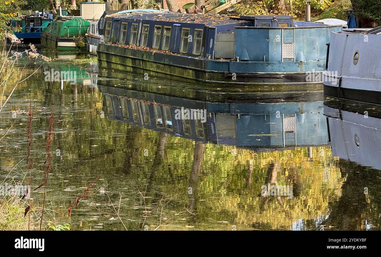 Schmale Boote, die auf dem Leeds- und Liverpool-Kanal mit Reflexionen im stillen Wasser verankert sind. Adlington in der Nähe von Chorley, Lancashire, England Großbritannien Stockfoto