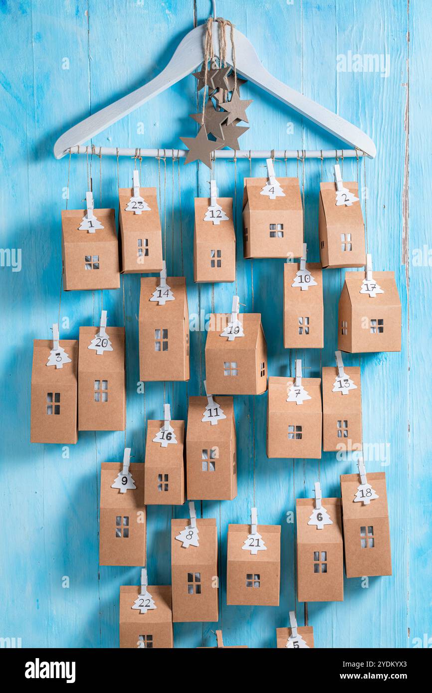 Spezieller Weihnachts-Adventskalender als kleines Haus mit einer Nummer auf blauem hölzernem Hintergrund Stockfoto