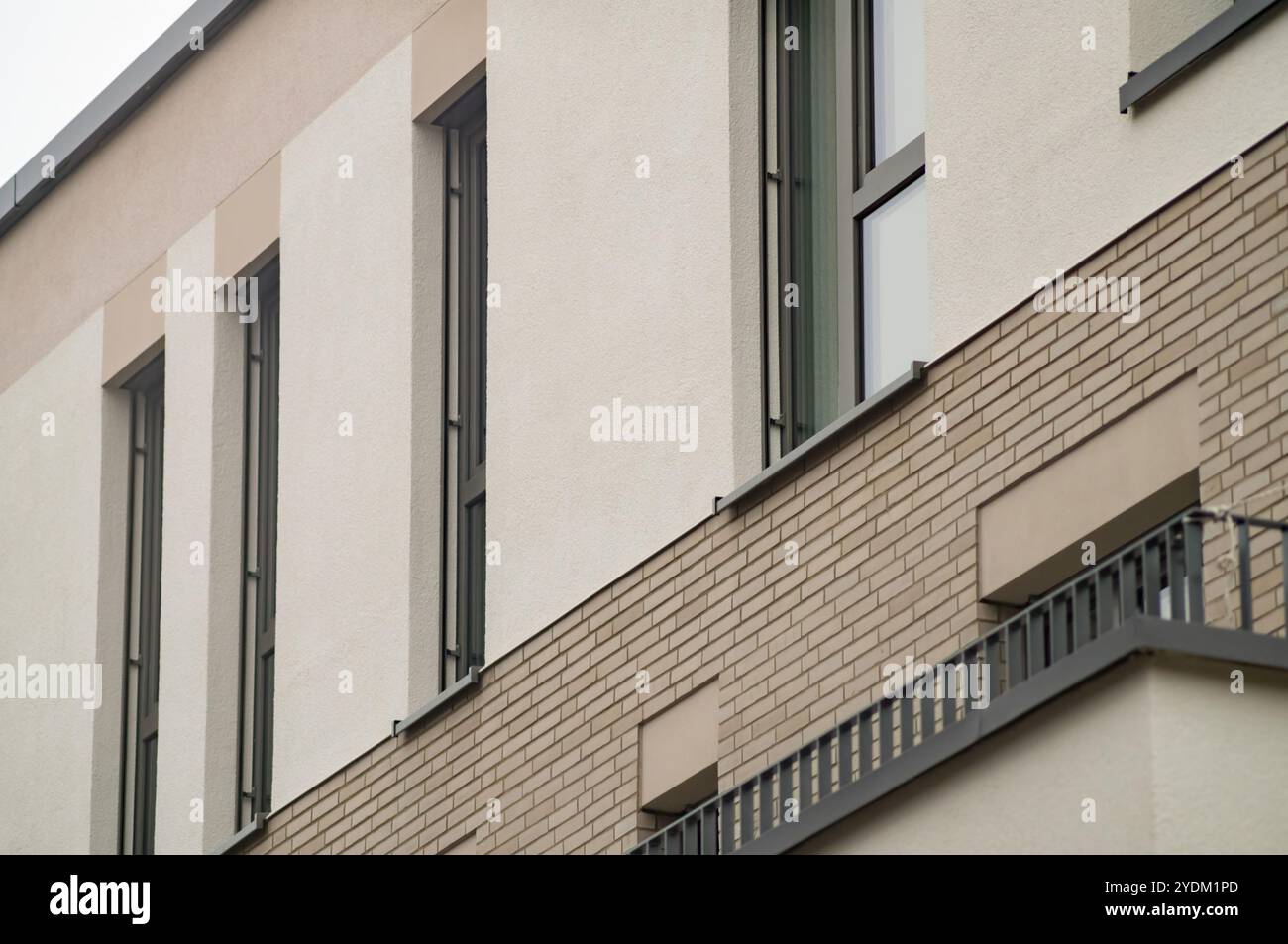 Modernes Wohngebäude mit zeitgenössischem architektonischem Design mit einer Kombination aus Ziegelstein- und Putzfassade, langen Fenstern und einem Balkendiagramm Stockfoto