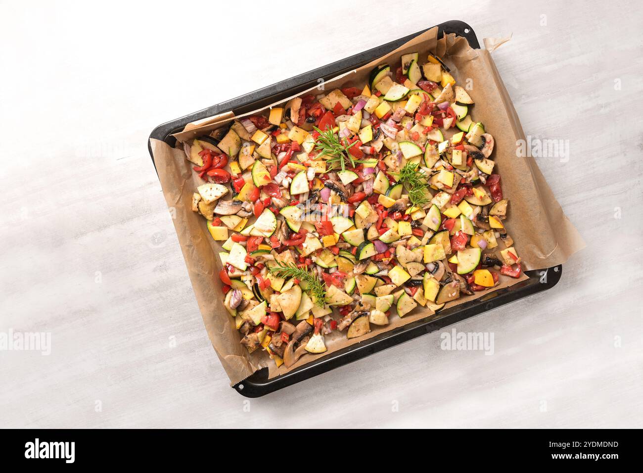 Gemüse auf Backpapier auf einem Tablett für den Ofen mit Zucchini, Paprika, Auberginen, Tomaten- und Rosmaringarnitur, gesundes vegetarisches Essen, hoher Ang Stockfoto