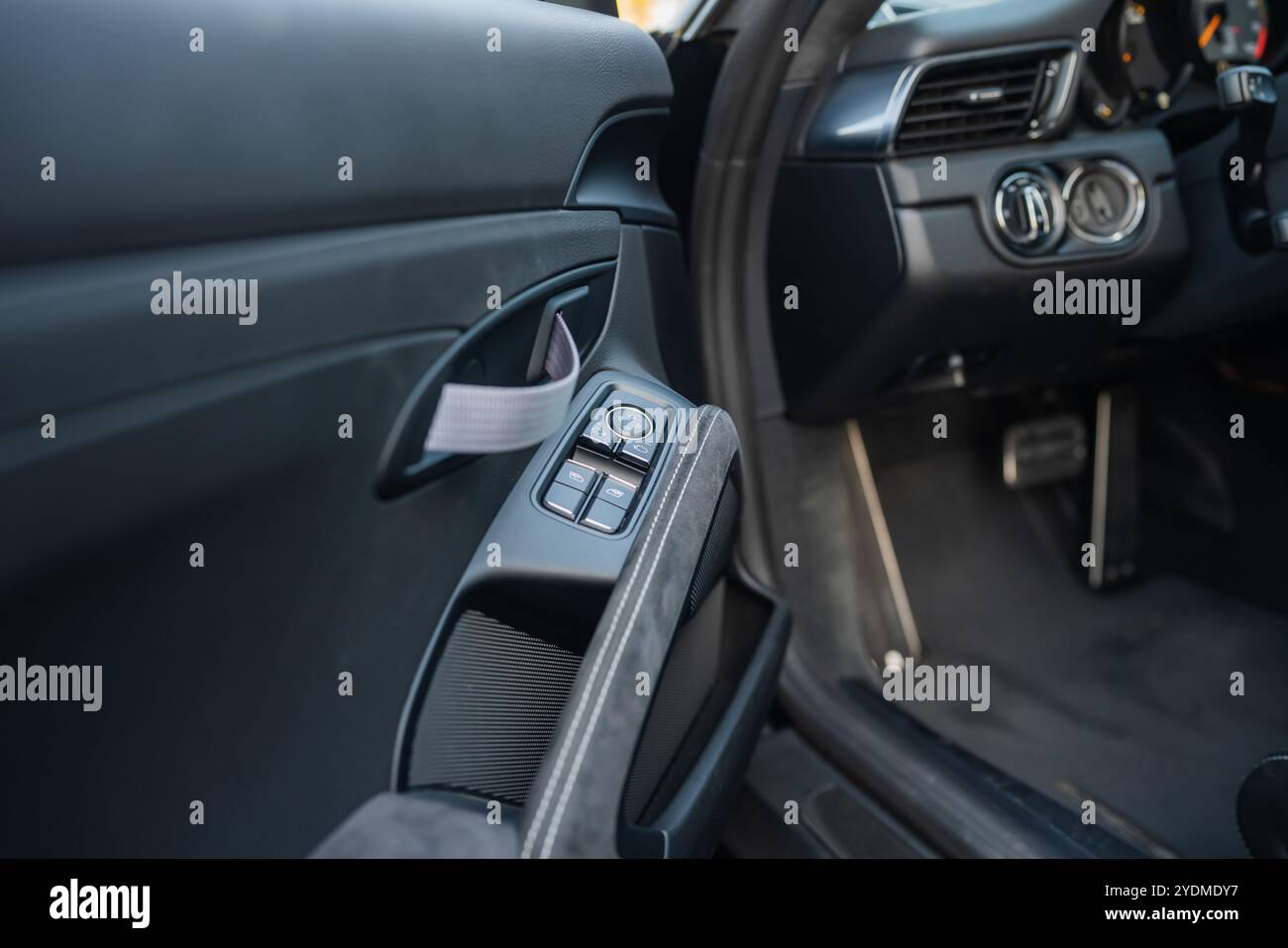 Luxuriöse Fahrzeugtür mit Fensterschaltern, Stoffriemen und Soft-Touch-Materialien. Stockfoto