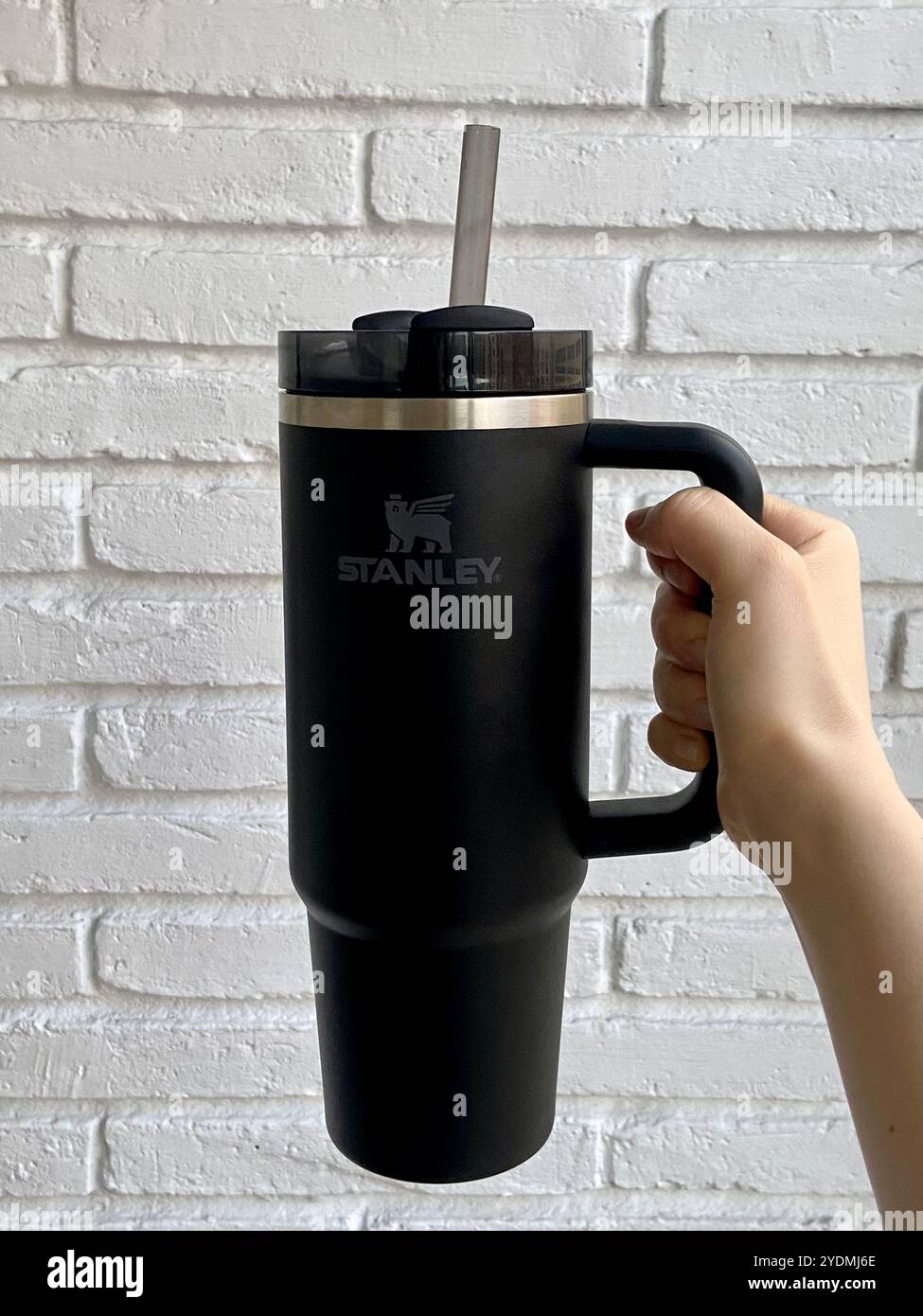 Barcelona, Spanien - 22. September 2024: Schwarzer Stanley Quencher H2.0 FlowState Tumbler mit Griff gegen weiße Ziegelwand Stockfoto
