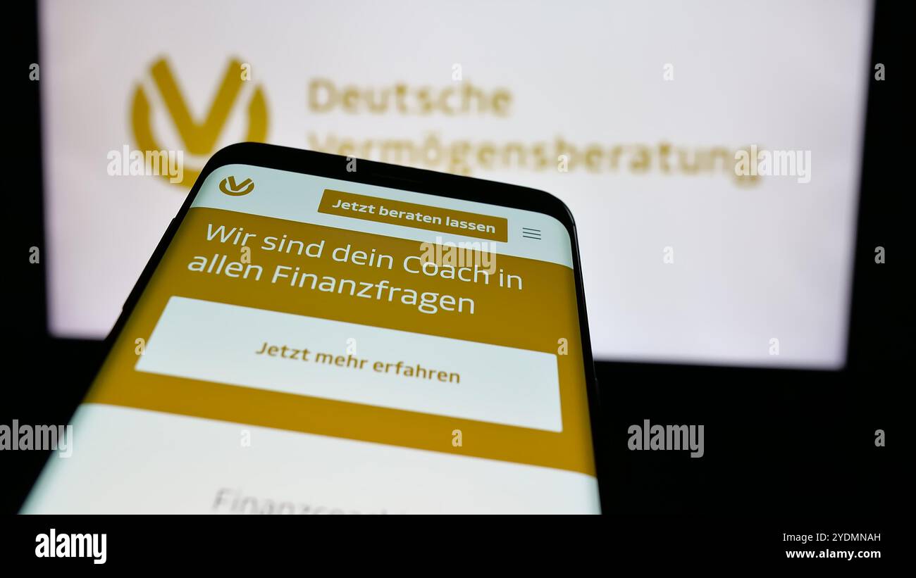 Mobiltelefon mit Website der Deutschen Vermögensberatung AG (DVAG) auf dem Bildschirm vor dem Firmenlogo. Fokussieren Sie sich oben links auf der Telefonanzeige. Stockfoto