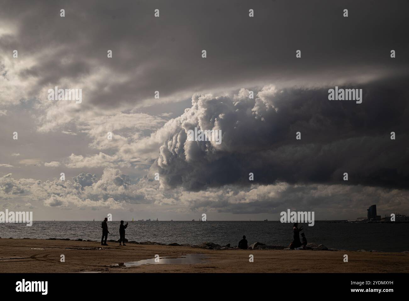 27. Oktober 2024, Barcelona, Spanien: In Barcelona laufen die Menschen an einem Wellenbrecher entlang, während stürmische Wolken den Himmel bedecken. Bild: Jordi Boixareu/Alamy Live News Stockfoto